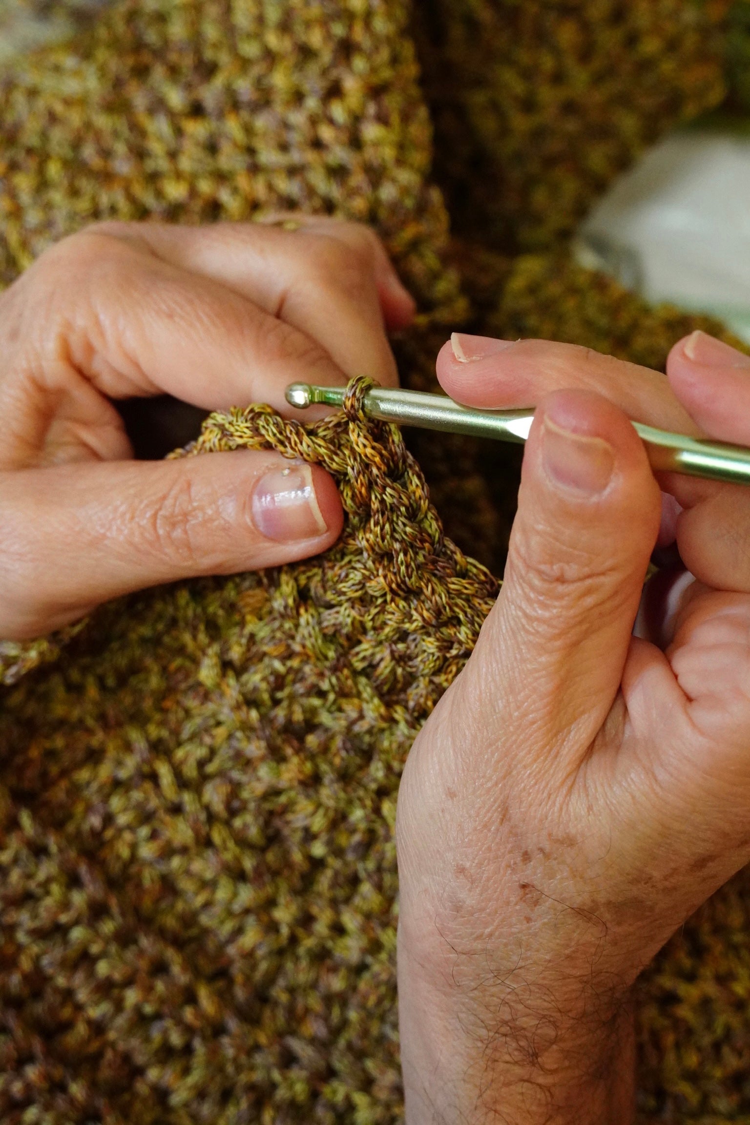 Hands working crochet stitches